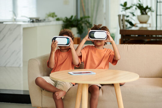 Siblings in headsets playing virtual reality game at home