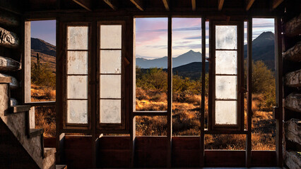 Old west desert landscape viewed through the damaged wall of an old cabin composite photo