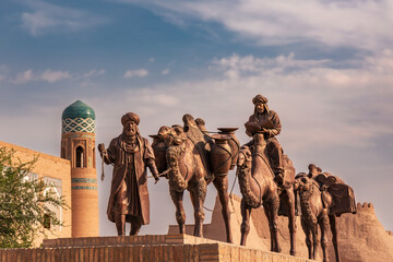 Sculpture of camels carrying goods along Silk Road and men in traditional dress, Khiva, Uzbekistan