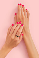 Womans hands with trendy manicure on pastel pink background. Beauty salon concept.