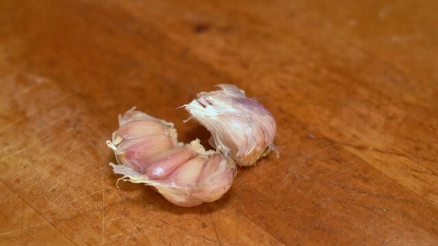 Clove of garlic is crushed on the kitchen table with a knife blade close-up