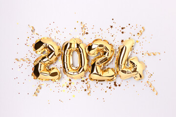 2024 gold colored foil balloons, shiny stars and ribbons confetti on a blue background. New Year concept.