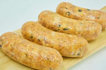 Raw sausages or sausages lie on a wooden board. Semi-finished product, ready for baking, frying or cooking. White background.
