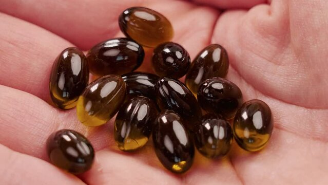 Medicinal cannabis pills. Cannabidiol (CBD) pharmaceutical capsules with marijuana oil in hand close up