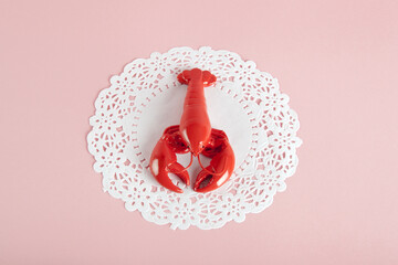 a red metal lobster on a white doily