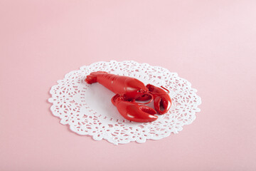 a red metal lobster on a white doily