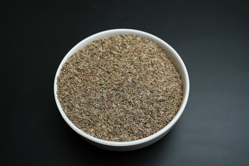Dill seed in a white plate on a black background