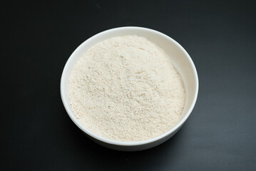 dry garlic powder in a white plate on a black background