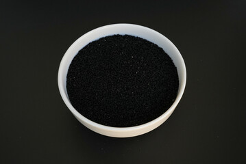 Nigella sativa seeds in a white plate on a black background