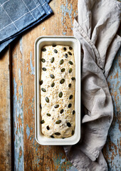 Homemade bread dough with seeds in a baking tray. Top view. Rustic wooden background