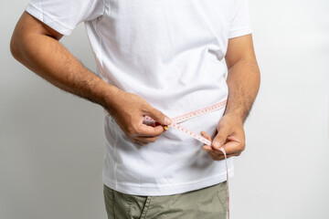 Man touching his fat belly on white background. Paunch of a man. Overweight tape measure around the waist