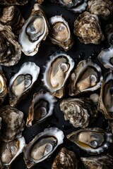 Creative flatlay pattern with Fresh oysters on black stone background with ice. Closeup open oyster. Seafood market or restaurant concept. French delicacy. Aphrodisiac mollusk