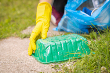 Woman hand collection plastic garbage in nature. Female picking up trash in park. Earth Day April 22. Save planet. volunteer cleaning forest environment from rubbish pollution. World Environment Day