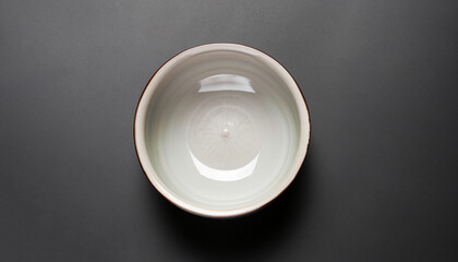 Ceramic bowl on black background, top view