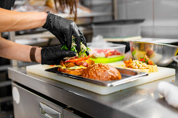 chef hand cooking cheese burger with vegetables and meat on restaurant kitchen