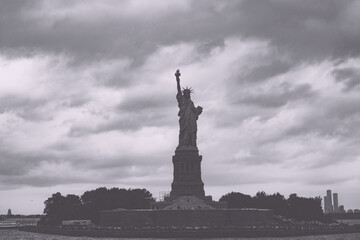 Fototapeta premium New York, New York, United States. August 07, 2023. Dramatic and detailed image of the Statue of Liberty with strong shades of green, sky with many clouds and very high resolution.