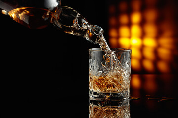 Pouring whiskey from a bottle into a glass.