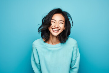 Obraz premium Smiling Asian Woman with a Cute Portrait on Blue Studio Background