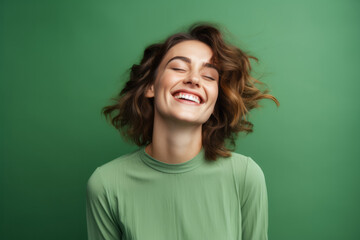 Smiling woman with a cute pose on a vibrant green studio background