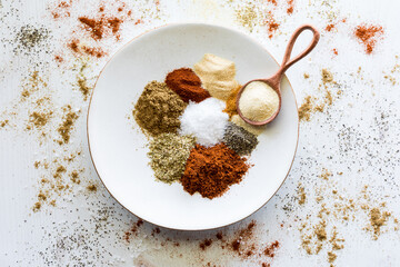 A plate with piles of spices used to make a taco seasoning blend.