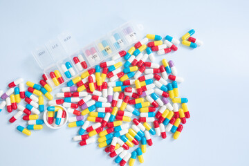 Daily pill box with medications and nutritional supplements on blue. Top view.