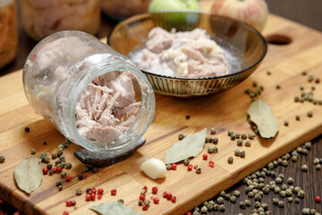 a jar of homemade stew on the table, next to a spoon and potatoes in a plate