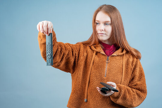 a woman contemptuously holds a remote control, a dirty remote control in her hands