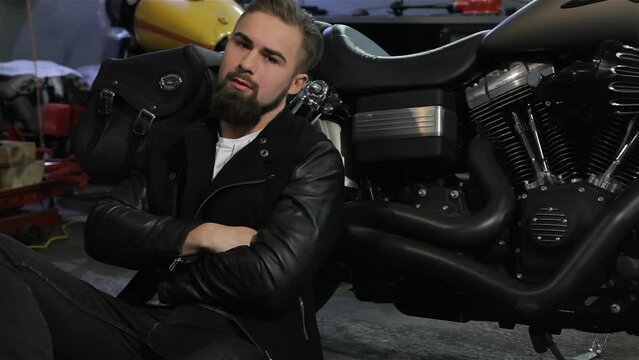 Male biker sits on the floor near the motorcycle