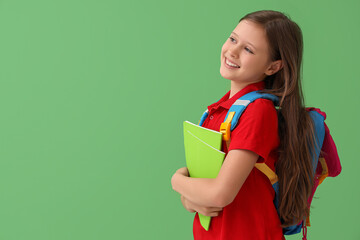 Little schoolgirl with copybooks on green background