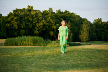 Adult energetic self-confident woman 50 years old, walking on the golf course