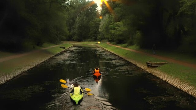 Family kayaking holidays. A family of parents with children kayaks in the evening at sunset. A pair of rowers on a kayak synchronously row with oars overtaking another team. Kayaking competitions.