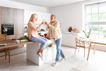 Obraz na płótnie Canvas Mature couple drinking champagne in kitchen