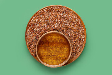 Wooden bowls with flax oil and seeds on green background
