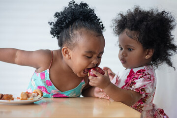 Cute African baby girl is feeding .her friend, sharing apple fruits for her friend, 1-2 years baby...