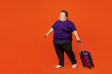 Traveler chubby overweight man wear purple casual clothes hold suitcase bag isolated on plain...