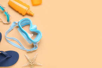 Swimming mask, goggles, flip flop and bottle of sunscreen on beige background