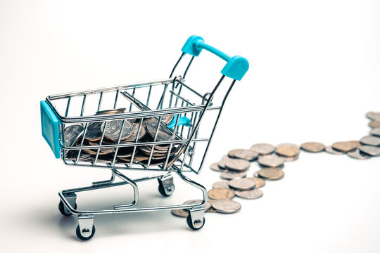 Supermarket trolley with scattered coins on a white background.