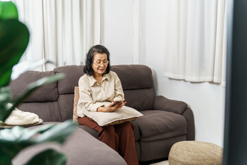Fototapeta premium Middle age Asian woman holding cell telephone. senior woman with smart phone. elderly woman using smartphone at home with technology concept