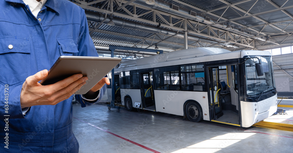 Poster Serviceman with digital tablet on the background of the bus in the garage.