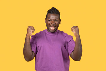 Fototapeta premium Emotional Black Man Shaking Fists Celebrating Big Luck In Studio