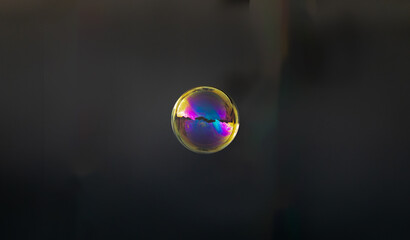 Gold soap bubble on blurred dark background. Close-up.