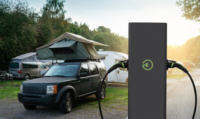 Close-up of a charging station for electric car against the backdrop of a campsite.