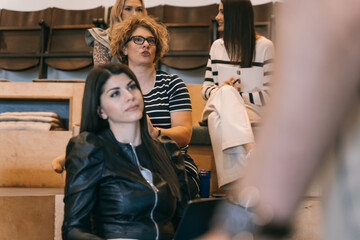 Senior female employee giving feedback to her business trainer during presentation in small amphitheater at the office