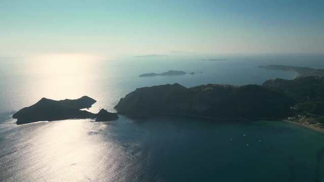 Drone aerial footage of Agios Georgios Beach, featuring its turquoise waters and sandy shoreline, set against the charming backdrop of rolling hills