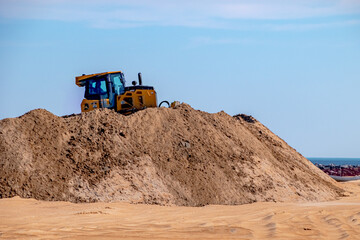 Obraz premium Heavy excavator working on the sand beach restoration
