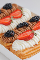 Top view french eclairs with creme and fresh berries blackberry and strawberry in gift box