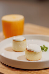 Closeup sweet syrniki, cottage cheese pancakes with white sauce, condensed milk. Healthy nutritious breakfast with orange juice