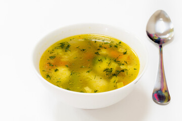 Appetizing soup with chicken balls, herbs and carrot and potatoes in white plate on white background