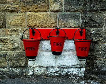Three red metal fire buckets hanging on the wall at Goathland station on the North York Moors Railway