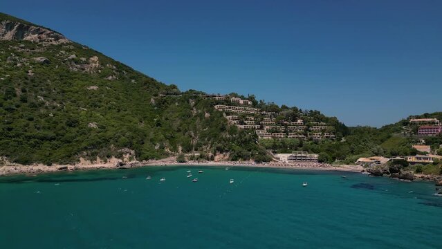 Drone footage of boats gently swaying in the sunny sea, moored not far from the Paralia Ermones Beach, on a hot day
